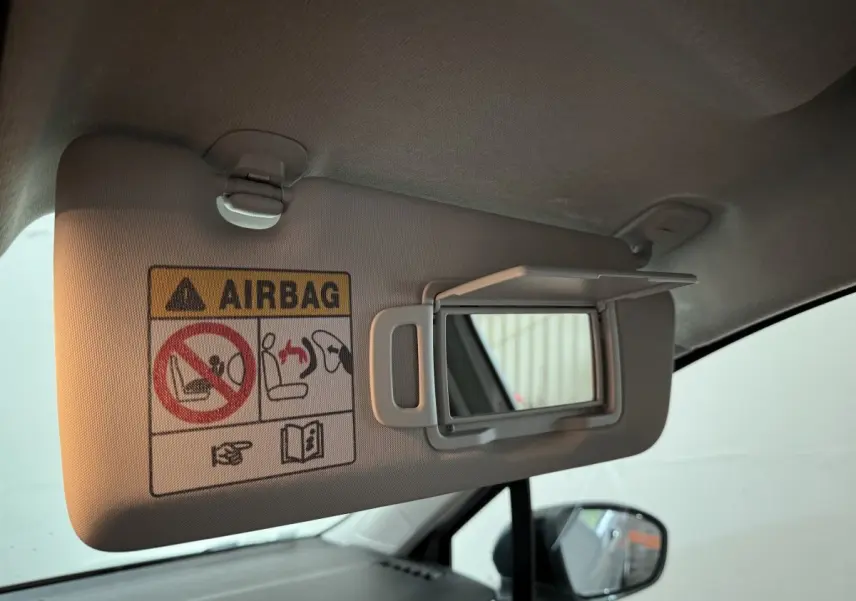 Détail du pare-soleil côté conducteur avec miroir ouvert et avertissement airbag dans une Renault Clio gris clair.