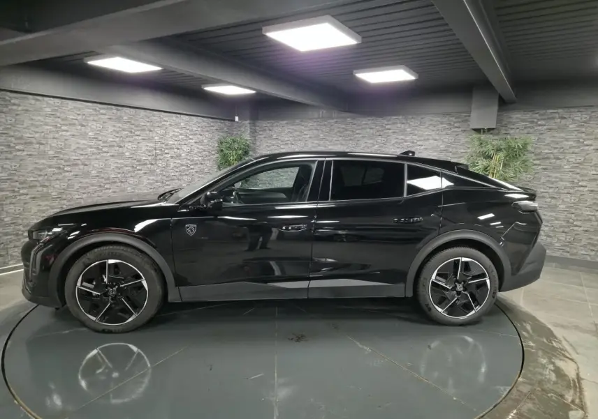 Peugeot 408 hybride noire vue de profil côté gauche, avec jantes alliage 19 pouces et toit plongeant.