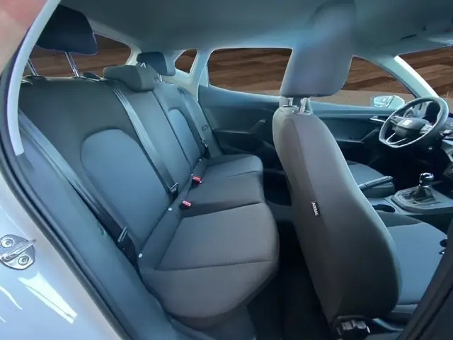 Intérieur de la SEAT Ibiza blanche 2023 vu côté droit, montrant les sièges arrière et avant en tissu gris avec volant multifonctions.