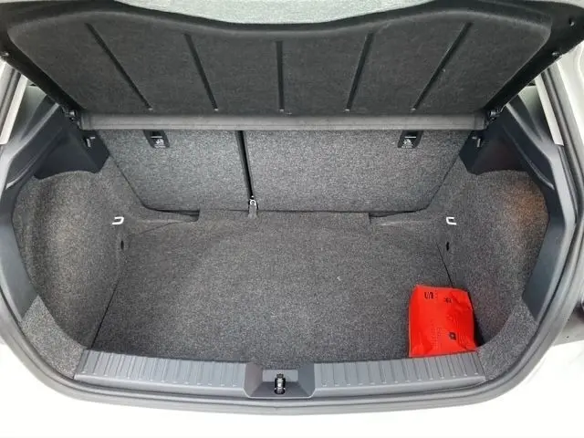 Coffre ouvert de la SEAT Ibiza blanche 2023, vue de dessus montrant l’espace de chargement et un kit de secours rouge.