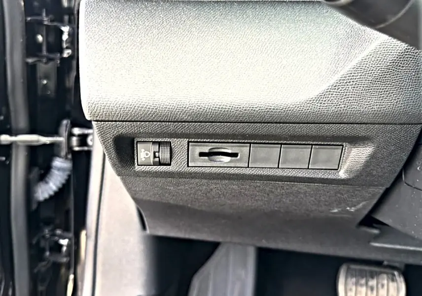 Détail intérieur côté gauche du tableau de bord noir avec commandes d’éclairage sur Peugeot 408 Hybrid 2024.