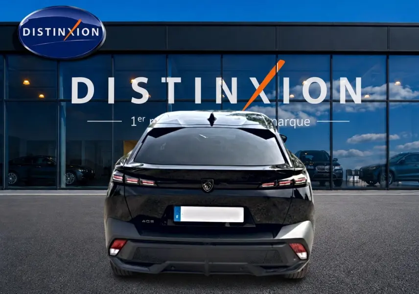 Vue arrière d'une Peugeot 408 Hybrid 136 allure noire, avec feux LED et lunette arrière surteintée, devant une vitrine Distinxion.