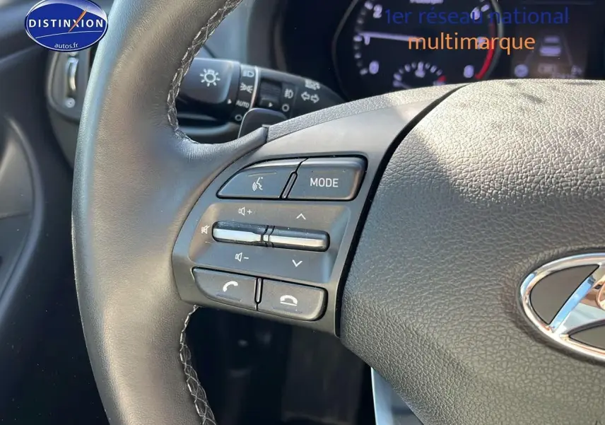 Gros plan sur le volant cuir de la Hyundai i30 gris argent 2024 avec commandes audio multifonctions intégrées