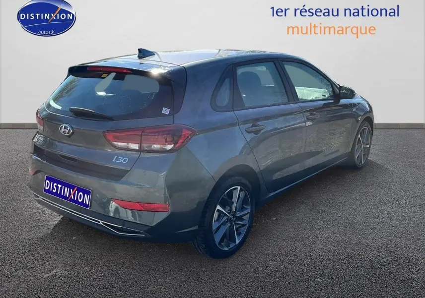 Vue 3/4 arrière droite d'une Hyundai i30 gris argent 2024 avec jantes alliage et feux arrière LED.
