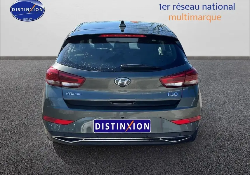Vue arrière d'une Hyundai i30 gris argent 2024 avec feux LED et logo distinctif sur un fond neutre.