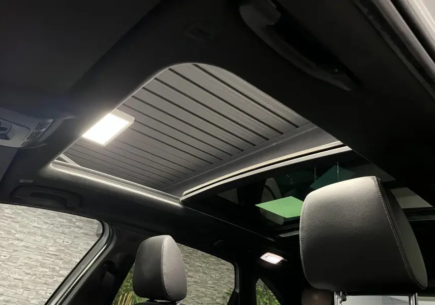 Vue intérieure du toit ouvrant panoramique en verre et des appuie-têtes en cuir noir d'une BMW Série 2 Active Tourer gris.
