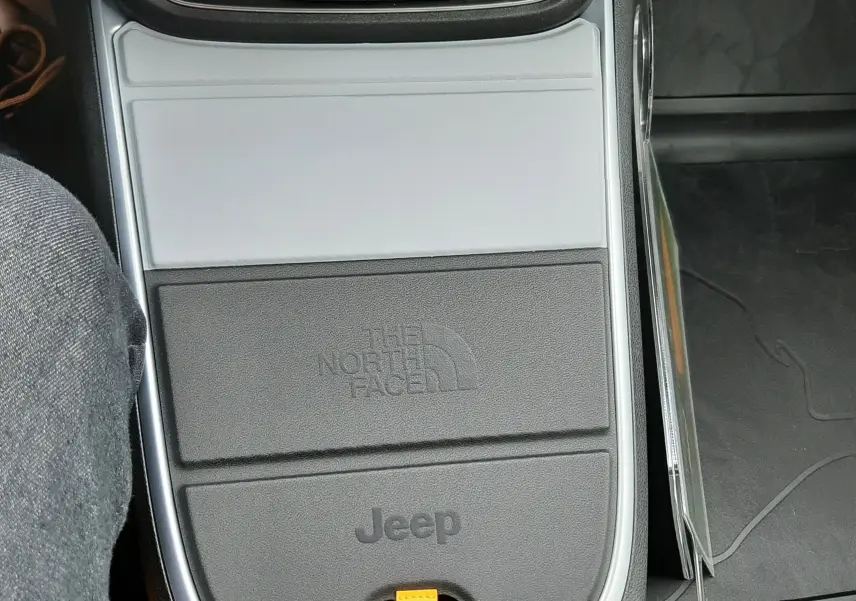 Vue rapprochée de la console centrale grise et noire du Jeep Avenger 2025 avec logo The North Face et commandes de boîte auto.