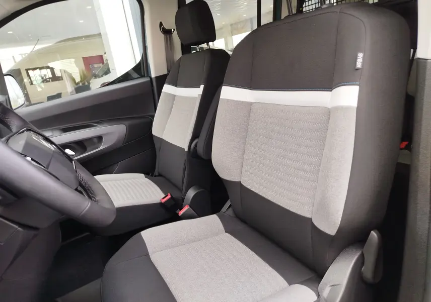 Vue intérieure côté conducteur du Citroën Berlingo 2025, sièges tissu gris et noir avec détails blancs et bleu.