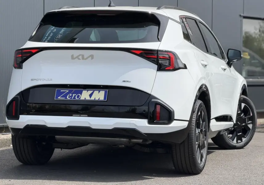 Vue 3/4 arrière droite du KIA Sportage blanc 2026 avec feux arrière LED et jantes alliage noires.