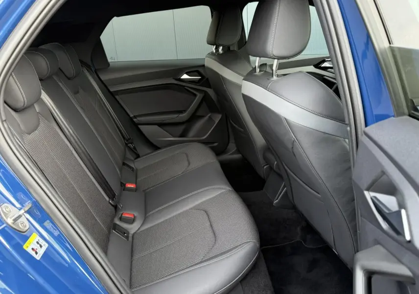 Vue côté gauche de l'habitacle arrière d'une Audi A1 Sportback bleu Ascari avec sièges sport cuir/tissu noirs.