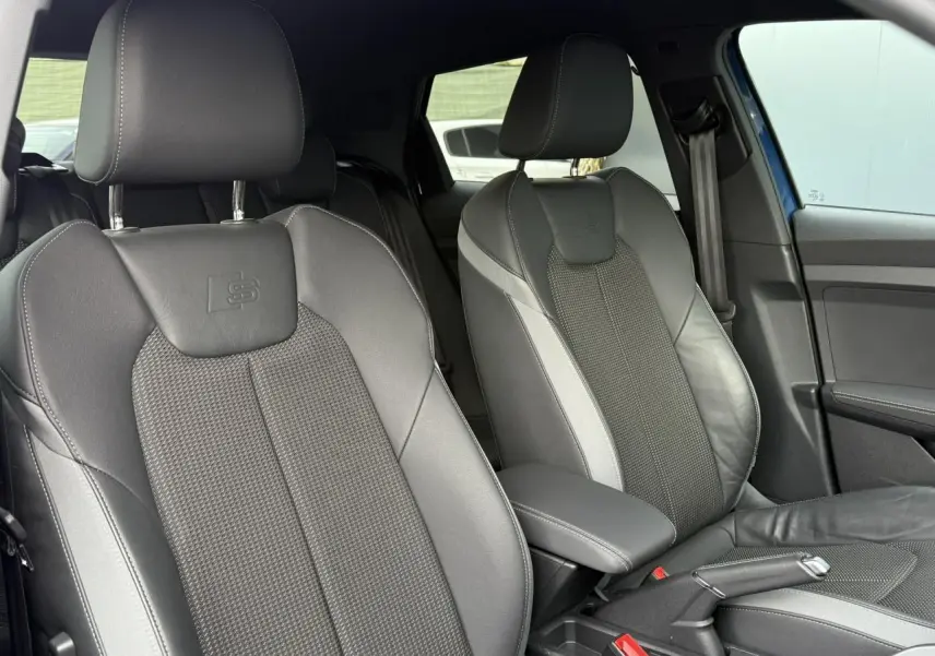 Gros plan sur les sièges avant sport cuir/tissu noirs avec logo S line dans l'Audi A1 Sportback bleu Ascari 2023.