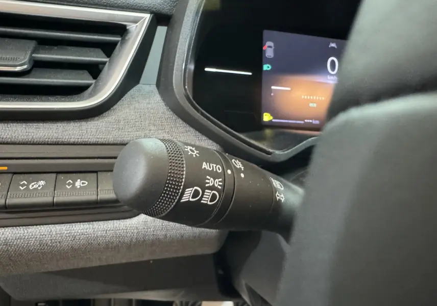 Gros plan sur la commande des phares et tableau de bord numérique de la Renault Clio gris clair, vue côté gauche.