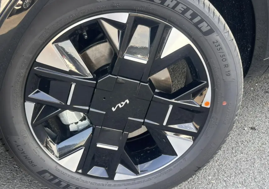 Gros plan sur la jante alliage 19 pouces noire et argentée du Kia Sportage 2026 avec logo Kia central.