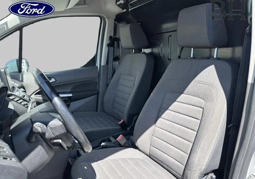 Vue intérieure côté conducteur du Ford Transit Connect gris, montrant les sièges avant et le volant multifonction.
