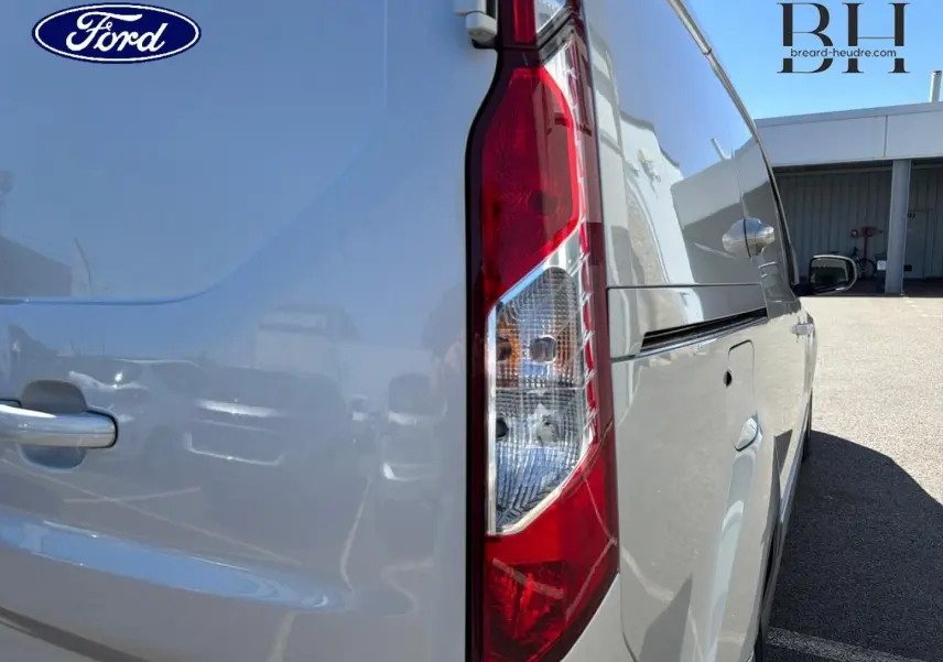 Vue arrière côté droit du Ford Transit Connect gris lunaire métallisé, mettant en valeur le feu arrière vertical et la porte latérale.