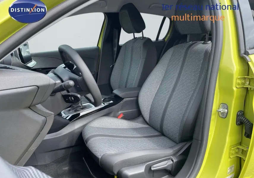 Vue intérieure côté conducteur d'une Peugeot 208 jaune Agueda Metal, sièges tissu gris et noir, volant et console visibles.