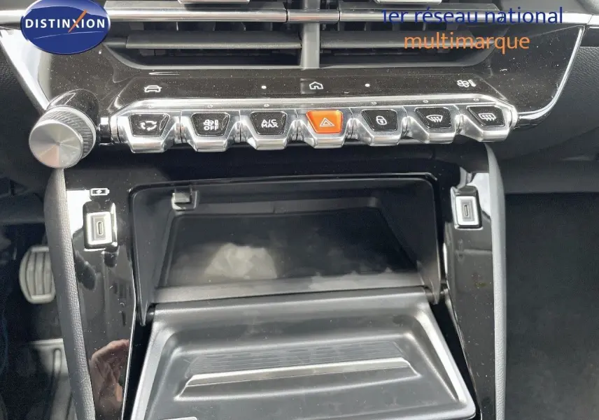 Vue rapprochée de la console centrale noire du Peugeot 208 2025 avec boutons de commande et rangement ouvert.