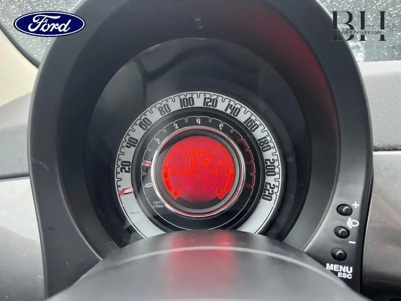 Vue rapprochée du compteur de vitesse circulaire de la FIAT 500 marron, avec affichage numérique rouge au centre.