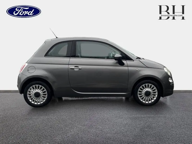 Profil droit d'une Fiat 500 marron métallisé de 2010, compacte avec jantes alu et toit panoramique en verre.