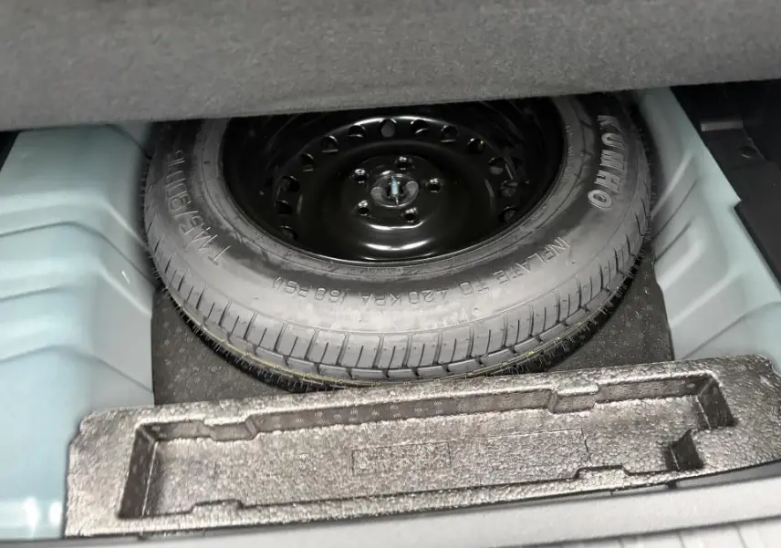 Vue rapprochée de la roue de secours noire dans le coffre du Renault Arkana 2025 Bleu Zanzibar Metal.