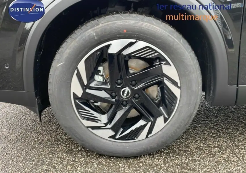 Gros plan sur la jante aluminium noire et argentée du côté gauche d’un Nissan Qashqai noir 2025.