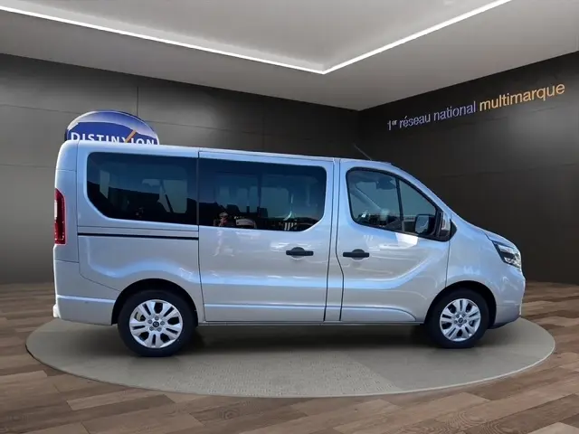 Vue latérale droite d’un Nissan Primastar gris clair 2025 en intérieur, avec portes latérales et jantes acier.