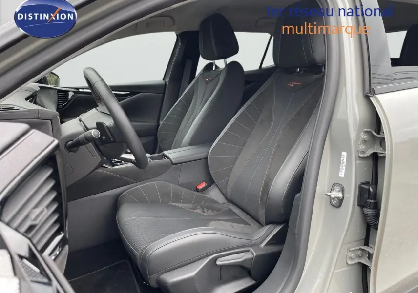 Intérieur côté conducteur du DS4 2024 gris laqué métal, sièges en cuir noir avec surpiqûres rouges visibles.