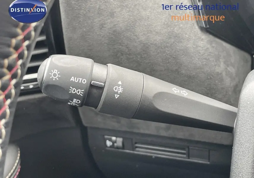 Le commodo d'éclairage et clignotant du DS4 2024 en gros plan avec volant cuir noir sur fond intérieur gris.