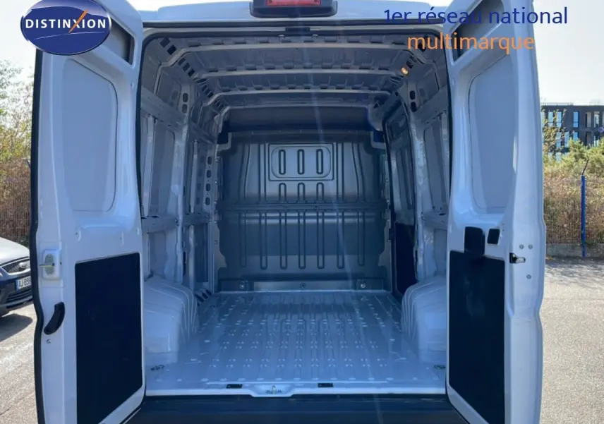 Vue arrière des portes ouvertes du Peugeot Boxer Fourgon blanc banquise, montrant l’espace de chargement vide et métallique.
