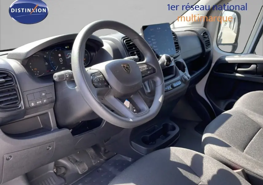 Vue intérieure côté conducteur du Peugeot Boxer Fourgon 2025, tableau de bord noir avec écran tactile central et volant multifonction.