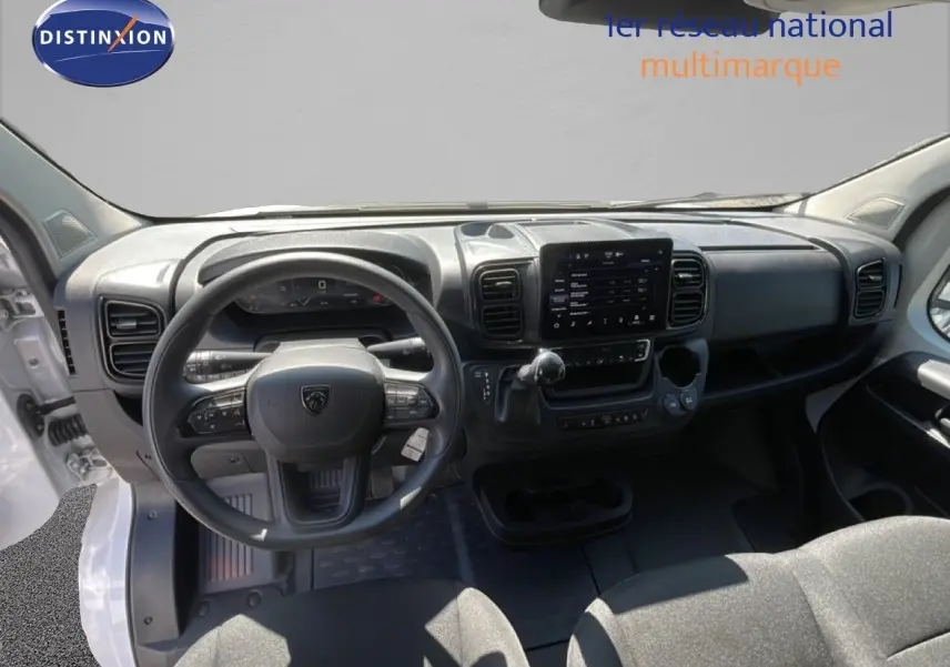 Vue intérieure avant du Peugeot Boxer Fourgon blanc banquise, montrant le volant, tableau de bord et écran tactile central.