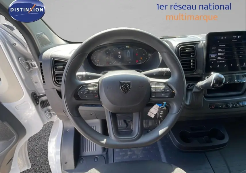 Vue intérieure centrée sur le volant Peugeot d'un Boxer Fourgon blanc banquise avec tableau de bord digital et écran tactile.
