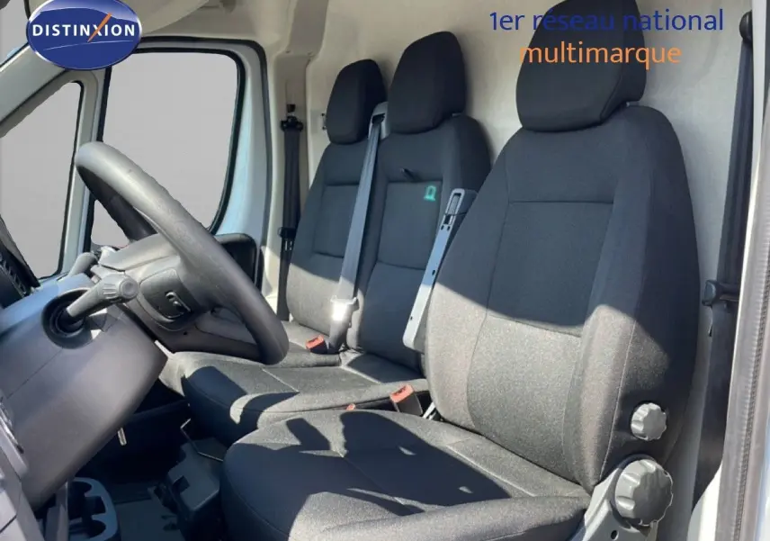 Vue intérieure côté conducteur du Peugeot Boxer Fourgon 2025, montrant les sièges noirs et le volant à gauche.
