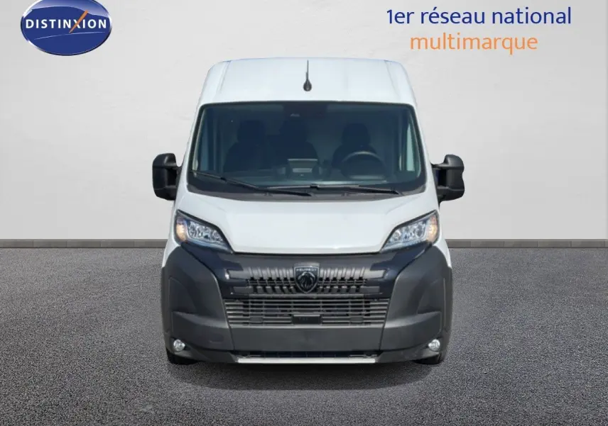 Vue de face du Peugeot Boxer Fourgon blanc banquise avec calandre noire et phares allumés sur fond neutre.