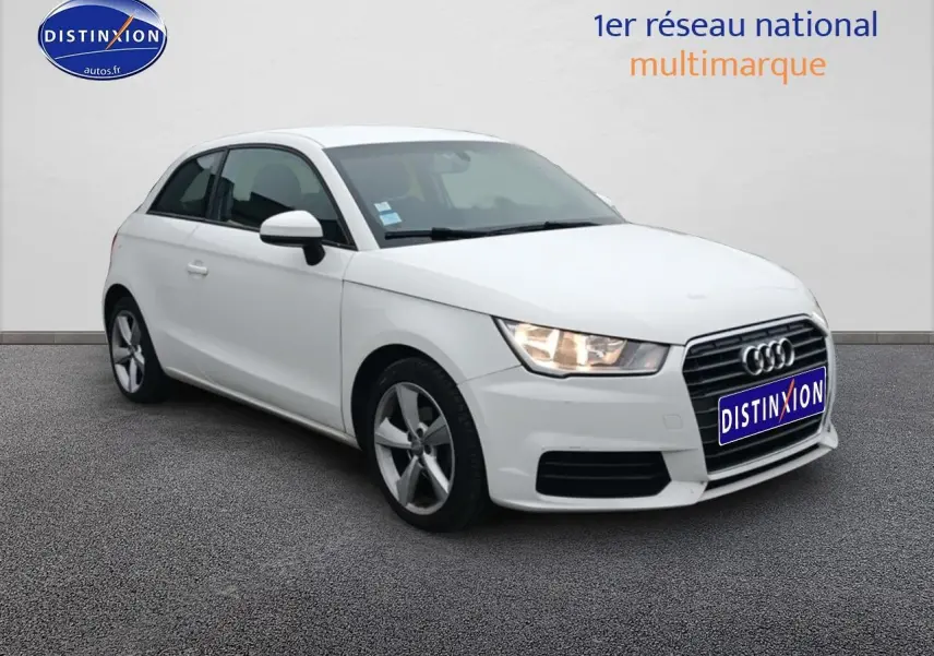 Audi A1 blanc en 3/4 avant droit avec jantes alu et phares allumés sur fond neutre.