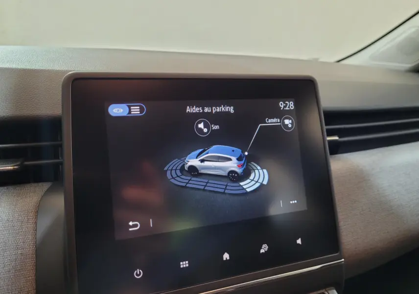 Écran tactile central montrant l'aide au stationnement avec vue 3D d'une Renault Clio gris foncé.