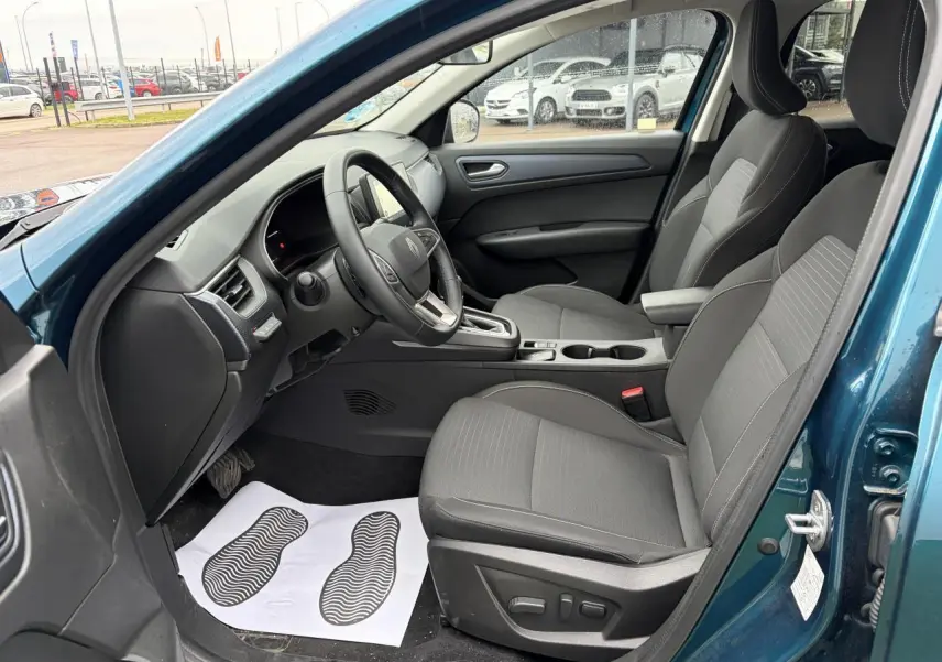 Vue intérieure côté conducteur du Renault Arkana bleu Zanzibar, sièges gris avec réglage électrique et console centrale visible.