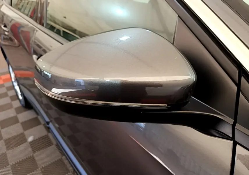 Rétroviseur électrique rabattable gris clair du côté gauche d’un Peugeot 5008, vue rapprochée en intérieur.