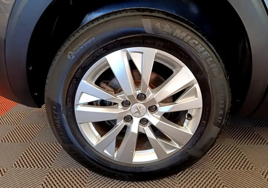 Gros plan sur la roue avant droite du Peugeot 5008 gris clair, avec jante alliage et pneu Michelin.