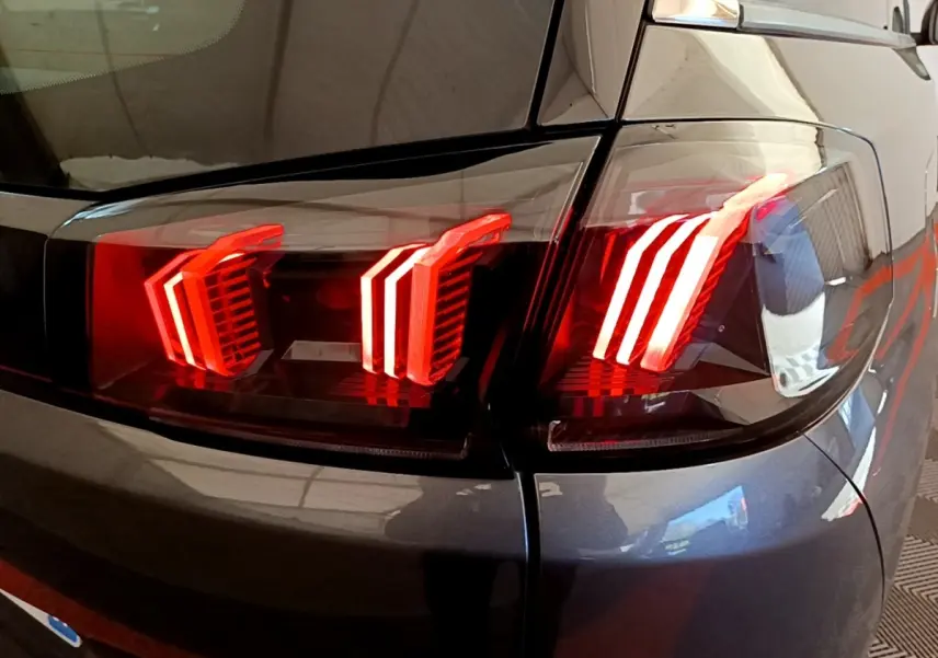 Gros plan sur les feux arrière LED rouges du côté droit d’un Peugeot 5008 gris clair de 2021.