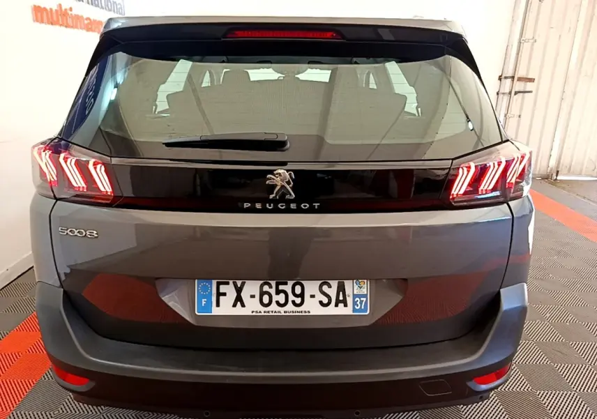 Vue arrière d’un Peugeot 5008 gris clair avec feux LED distinctifs en forme de griffes et plaque d’immatriculation française.