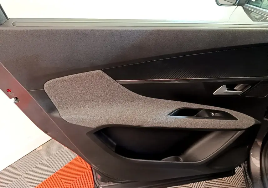 Vue intérieure côté gauche de la porte avant gris clair du Peugeot 5008 avec garniture tissu et plastique noir.