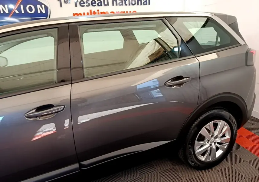 Vue côté droit arrière d'un Peugeot 5008 gris clair avec jantes alliage et poignées de porte chromées.