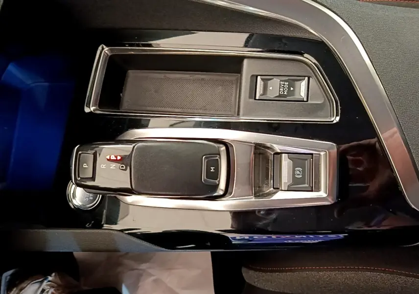 Vue rapprochée de la console centrale noire brillante du Peugeot 5008 2021, avec levier de vitesse automatique et bouton Drive Mode.