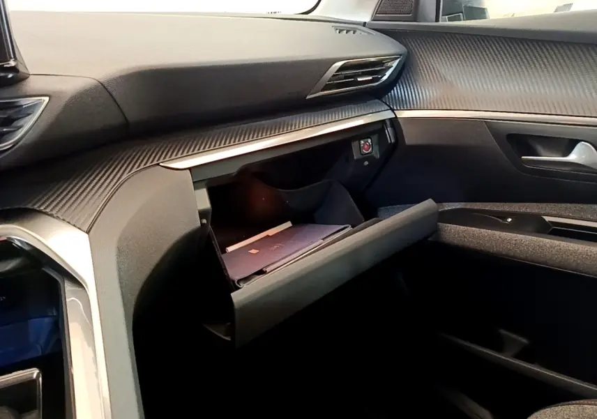 Vue intérieure côté passager du tableau de bord gris foncé avec boîte à gants ouverte du Peugeot 5008 2021.