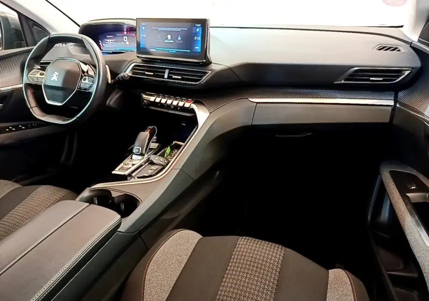 Intérieur Peugeot 5008 gris, vue côté passager avant, tableau de bord moderne avec écran tactile et volant compact cuir.