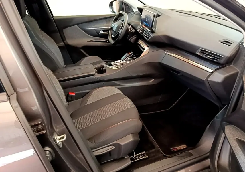 Vue intérieure côté conducteur du Peugeot 5008 gris clair, mettant en valeur le tableau de bord et l’écran tactile central.