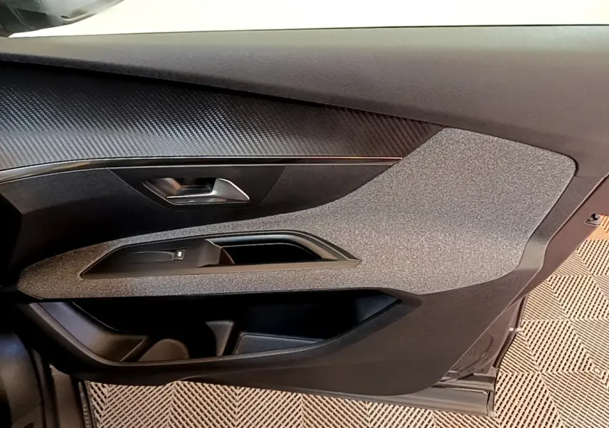 Vue rapprochée de la porte côté conducteur du Peugeot 5008 gris clair, mettant en valeur les matériaux texturés et la poignée intégrée.