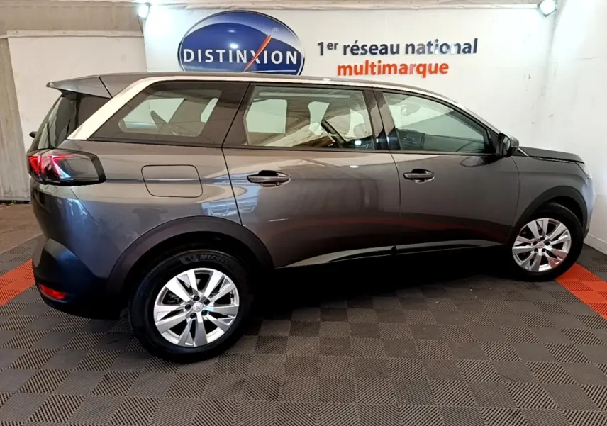 Vue de profil côté droit d’un Peugeot 5008 gris clair garé en intérieur avec jantes alliage et feux arrière LED.