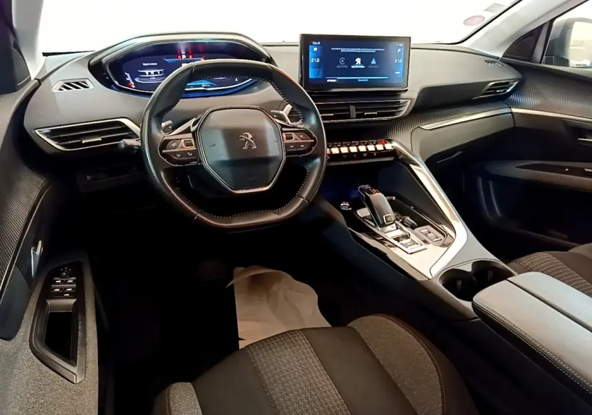 Vue intérieure avant du Peugeot 5008 2021, tableau de bord moderne avec écran tactile central et volant cuir multifonctions.